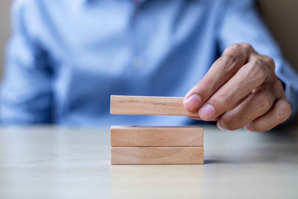 hand holding wooden building blocks on table background